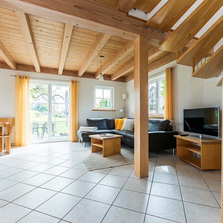 Wohnbereich mit Sofa und Blick aus der Tür ins Grüne