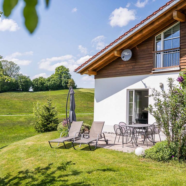 Terrasse mit Stühlen und Tisch und Liegestühlen mit Blick ins Grüne