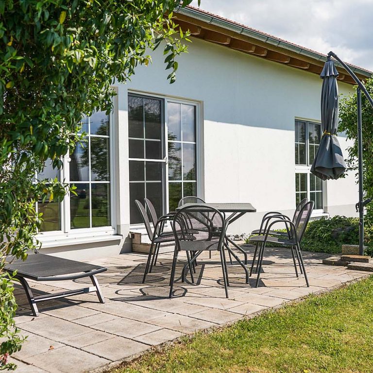 Terrasse mit Tisch und Stühlen und Liegestuhl